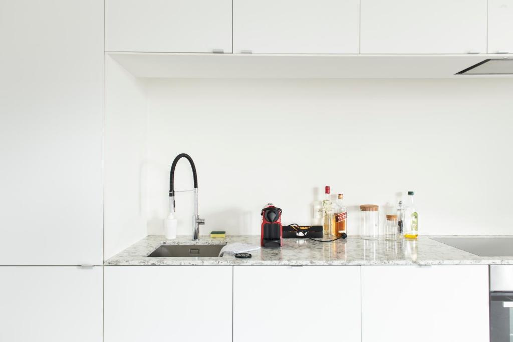 eine Küche mit weißen Schränken und einem Waschbecken in der Unterkunft Trendy Apartments as Base to Discover Ghent in Gent