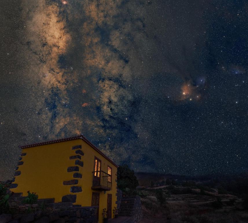 un edificio amarillo bajo un cielo estrellado por la noche en Casa Rural de Abuelo - Con zona habilitada para observación astronómica en Hoyagrande