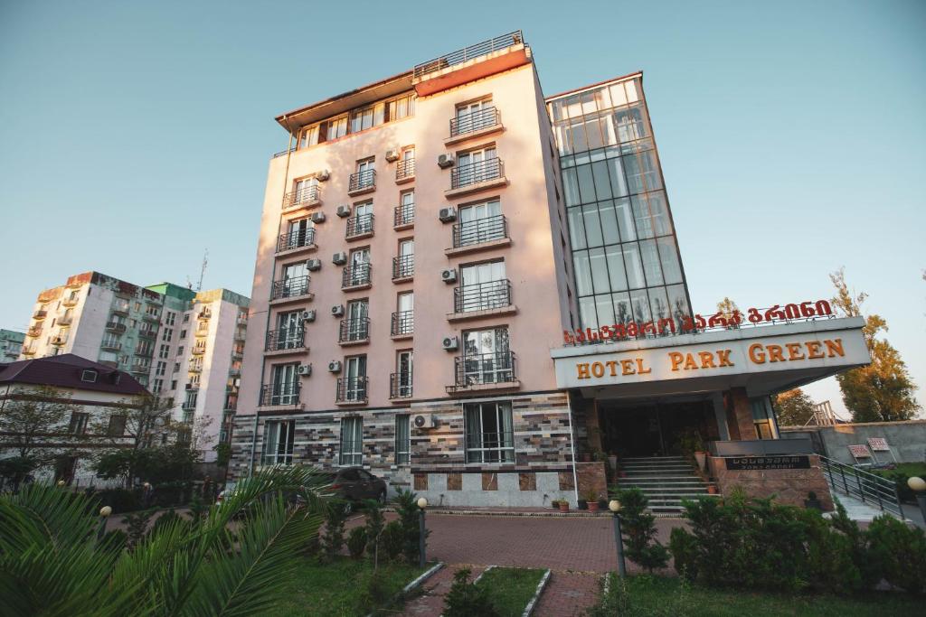 a large pink building with a hotel part green at Hotel Park Green in Poti