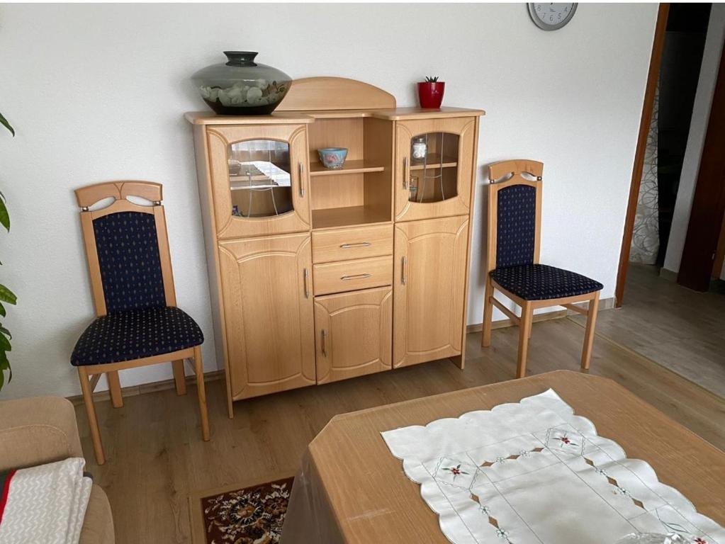 a room with a wooden cabinet and two chairs at Olgas Ferienwohnung Saarburg Bahnhofstraße 13G in Saarburg