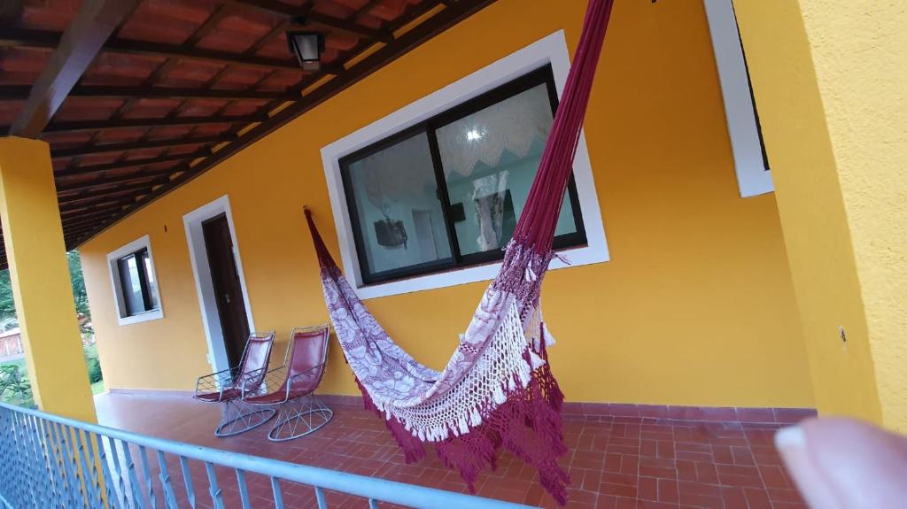 een veranda met een hangmat aan de zijkant van een huis bij Chacara Ceara in Monte Alegre do Sul