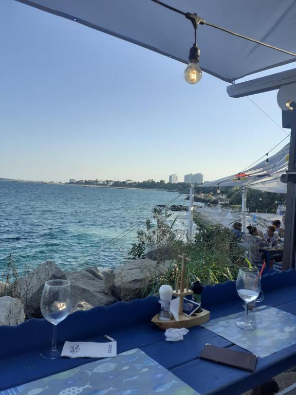 a table with two wine glasses and a view of the water at Garsonieră SORIN in Eforie Nord