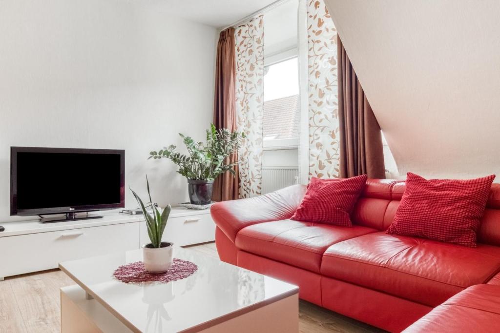 ein Wohnzimmer mit einem roten Sofa und einem TV in der Unterkunft Gutmensch Oberhausen 4 Schlafzimmer in Oberhausen