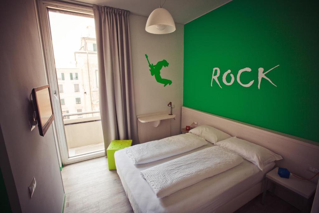 Un pequeño dormitorio con una pared verde y una cama en Hotel Nologo, en Génova