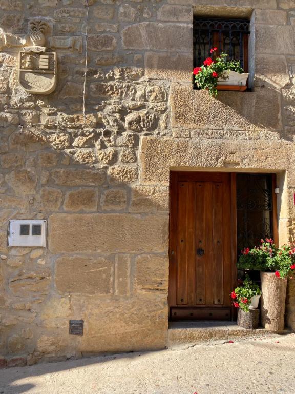 een stenen gebouw met een houten deur en bloemen bij Casa El Rubio in San Vicente de la Sonsierra
