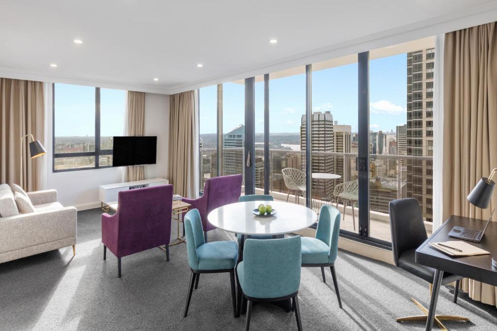 a hotel room with a table and chairs and a large window at Meriton Suites Pitt Street, Sydney in Sydney