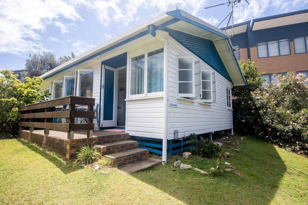 una pequeña casa blanca con escaleras delante de un edificio en Cabana - Original Straddie Beach Shack, en Point Lookout