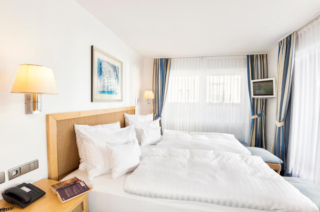 a hotel room with a large bed and a telephone at Strandhotel Juister Hof in Juist