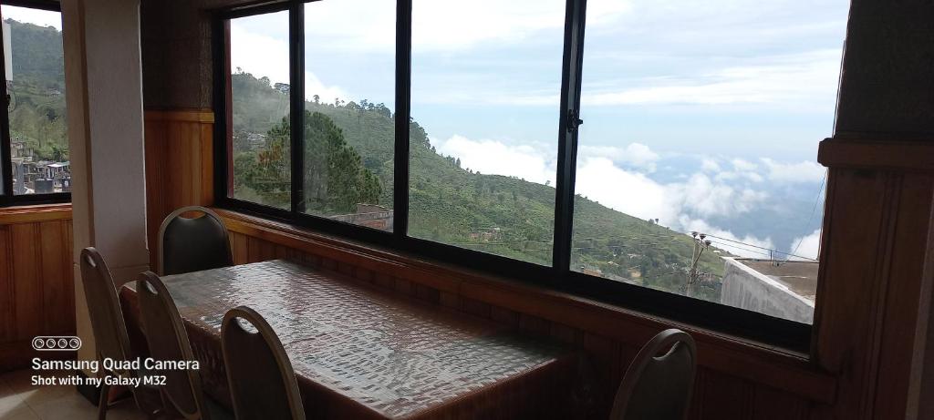 a table with a view of a mountain from a window at Highcliffe Guest House in Haputale