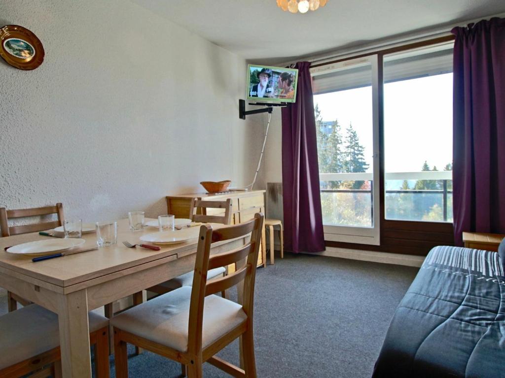 a dining room with a table with chairs and a television at Studio Chamrousse, 1 pièce, 6 personnes - FR-1-340-86 in Chamrousse