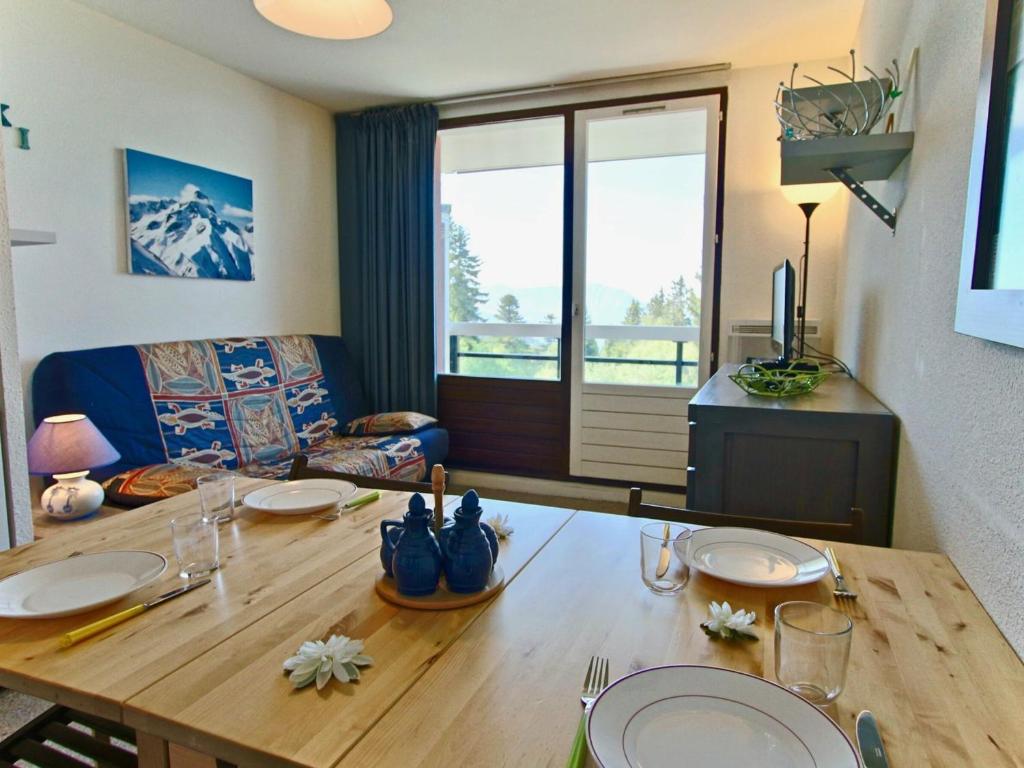 a living room with a wooden table with plates on it at Studio Chamrousse, 1 pièce, 4 personnes - FR-1-340-121 in Chamrousse