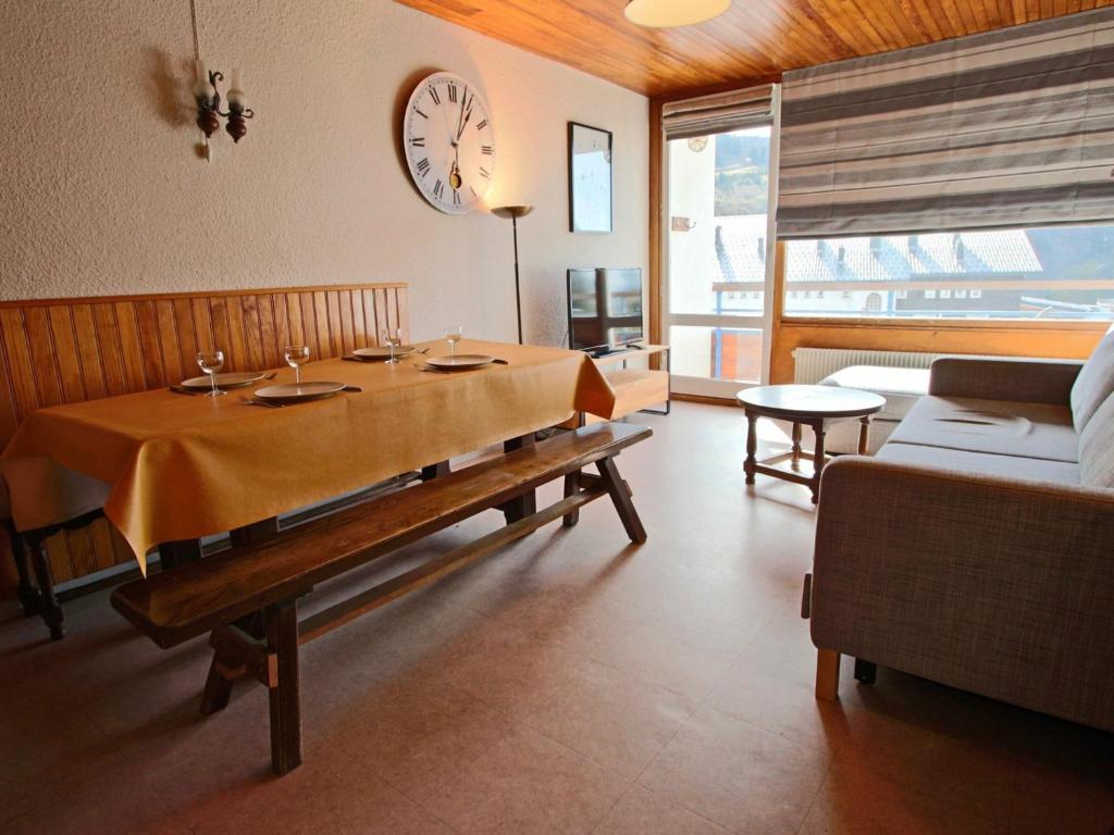 a dining room with a table and a clock on the wall at Appartement Chamrousse, 2 pièces, 6 personnes - FR-1-340-147 in Chamrousse