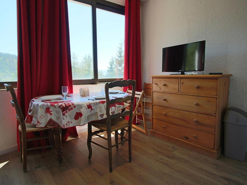 een eetkamer met een tafel en een dressoir met een televisie bij Studio Chamrousse, 1 pièce, 4 personnes - FR-1-340-218 in Chamrousse