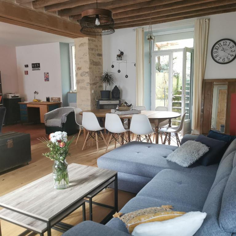 un salon avec un canapé bleu et une table dans l'établissement La Maison d'Estelle, à Corvol-lʼOrgueilleux