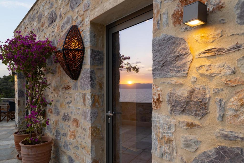 a stone wall with a door with a view of the ocean at Kechria Bay Villas in Skiathos