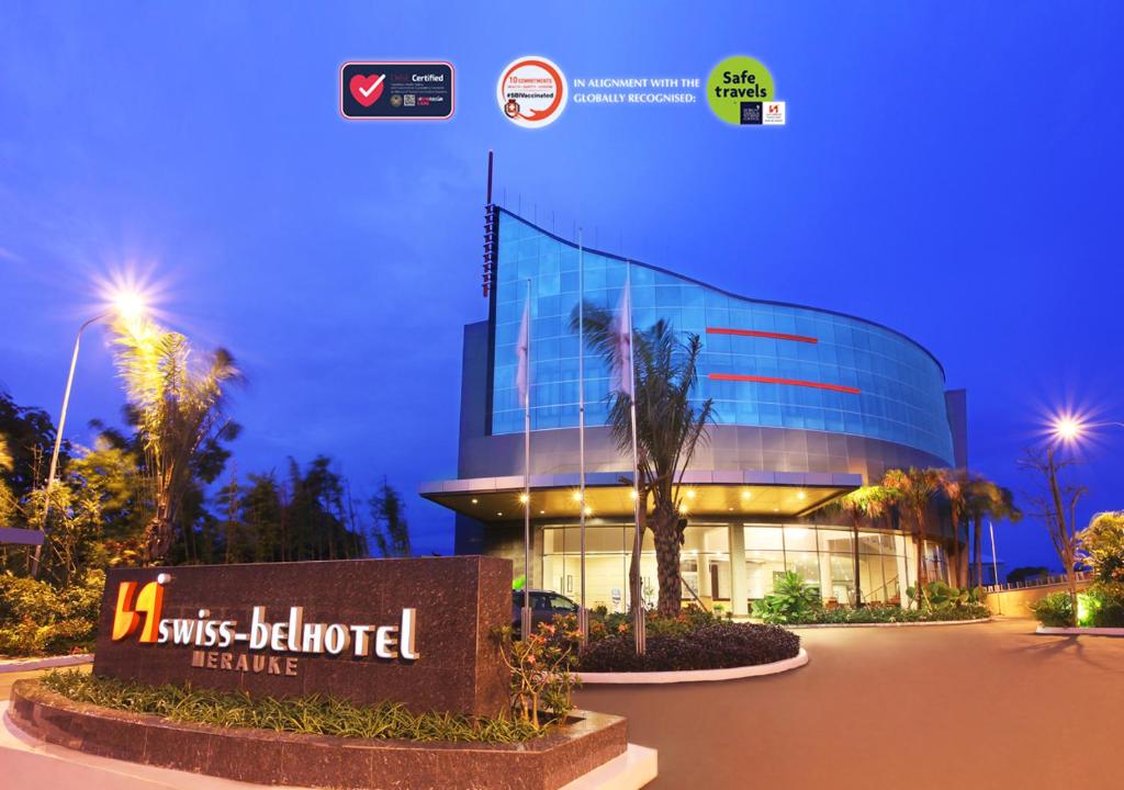 a glass building with a sign in front of it at Swiss-Belhotel Merauke in Merauke