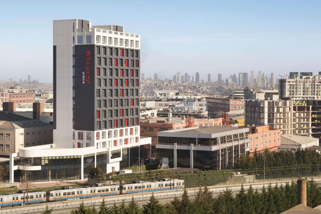 イスタンブールにあるラマダ アンコール イスタンブール バイランパサの都市の列車のある高層ビル