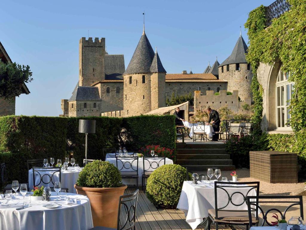 a patio with tables and chairs in front of a castle at Hotel de la Cité & Spa MGallery in Carcassonne