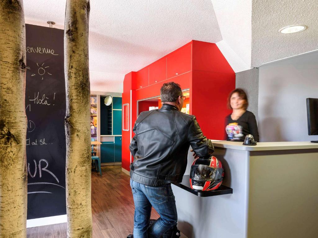 un homme debout devant un comptoir devant une femme dans l'établissement hotelF1 Lille Metropole, à Mons-en-Baroeul