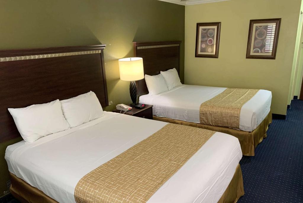 a hotel room with two beds and a lamp at Travelodge by Wyndham Odessa in Odessa