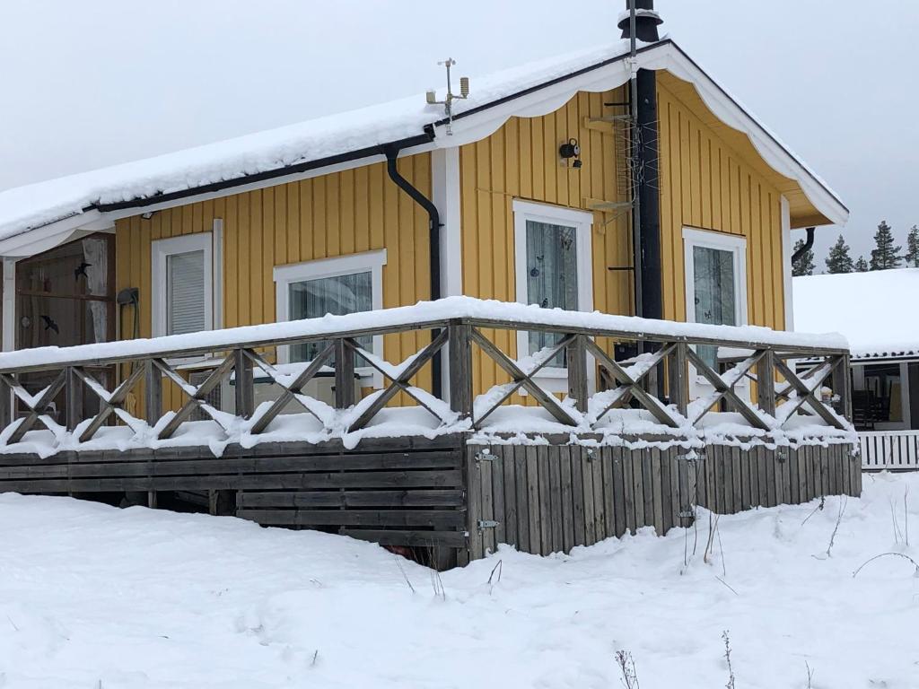 una casa amarilla con una valla de madera en la nieve en Vakantiewoning aan het water, en Råda