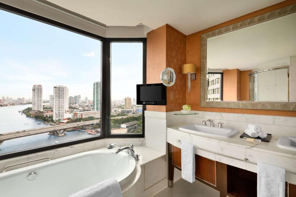 a bathroom with a tub and a large window at Shangri-La Bangkok in Bangkok