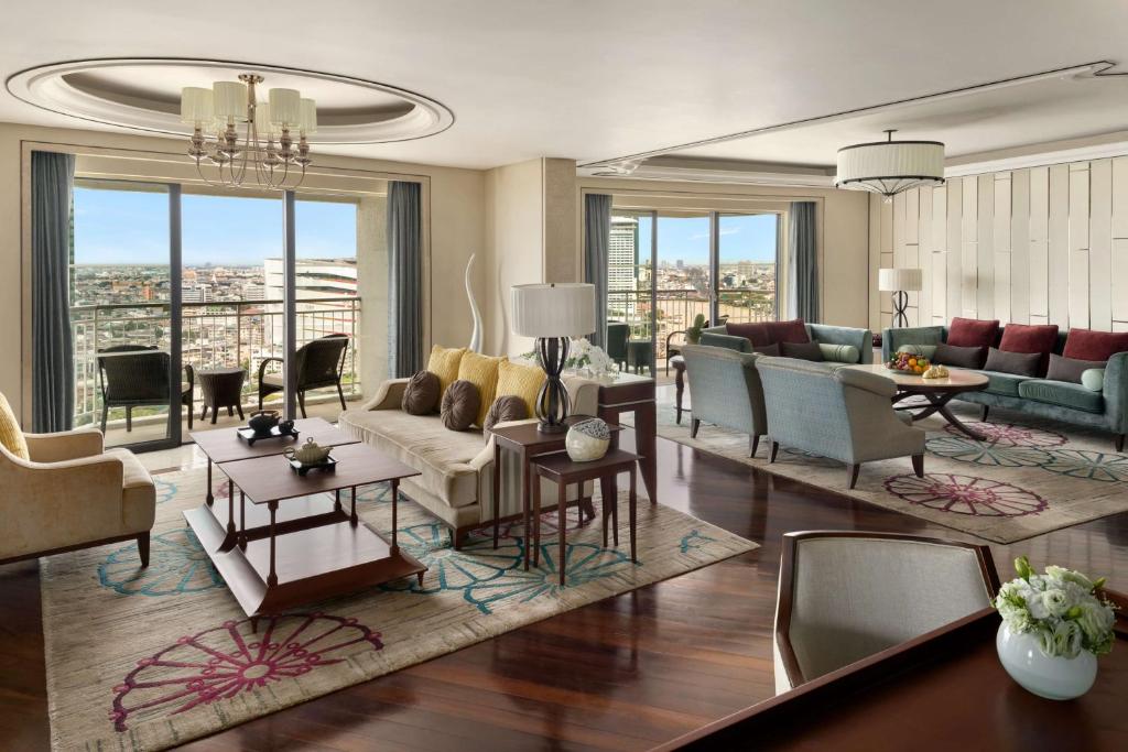 A broad sitting room with multiple sofas, a dining table and panoramic windows.