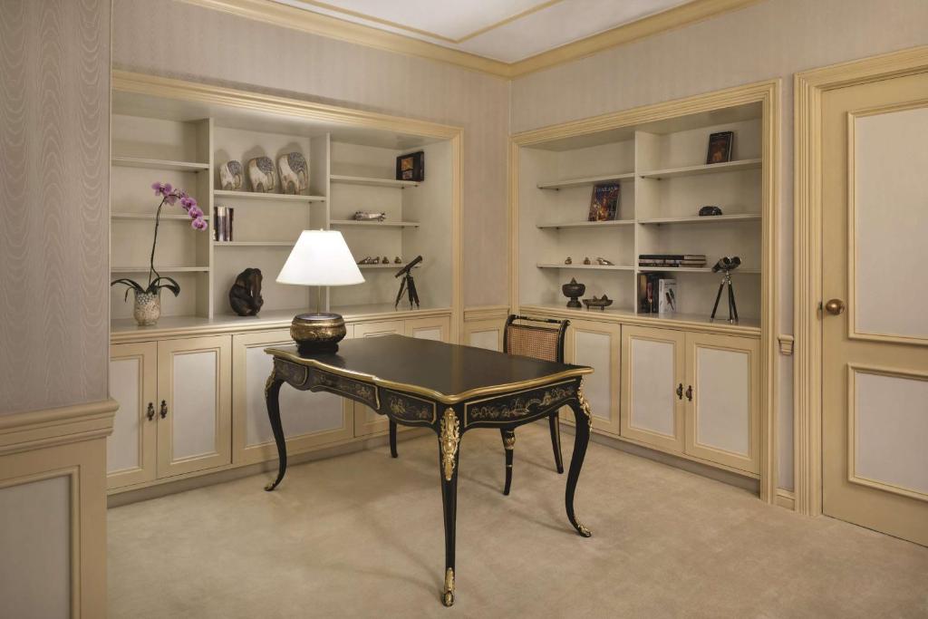 A private-looking writing room with an ornate desk and built-in display shelving.