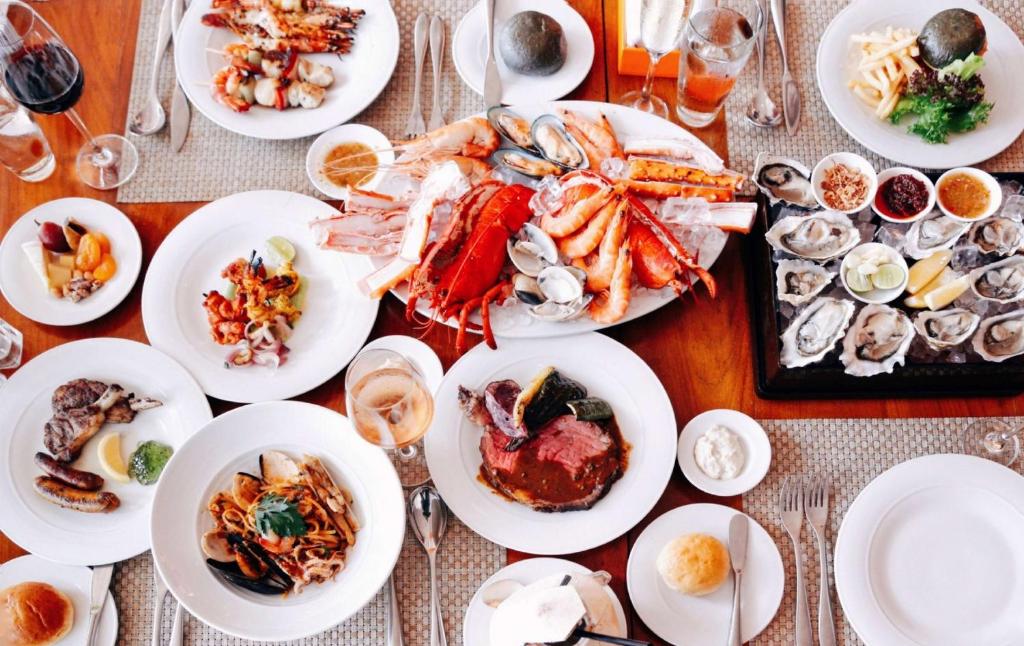 A lavish spread of seafood, meat, pasta, fruit, and desserts on a dining table.