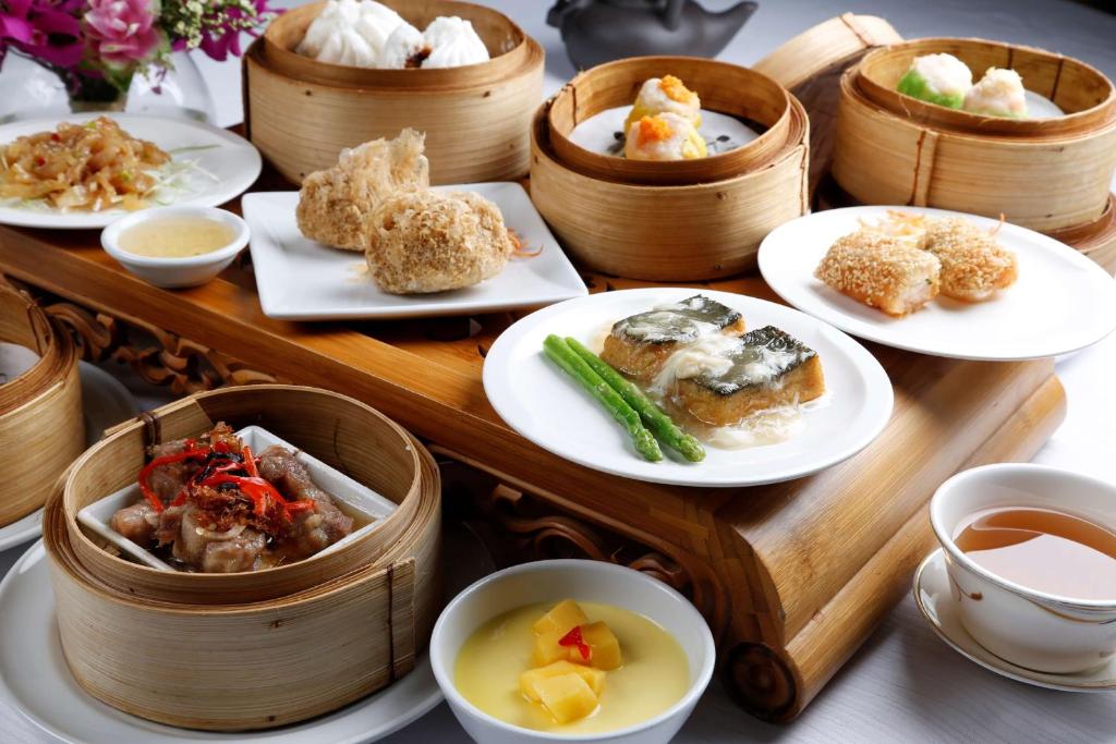 A generous spread of dim sum and Chinese dishes on a wooden table.