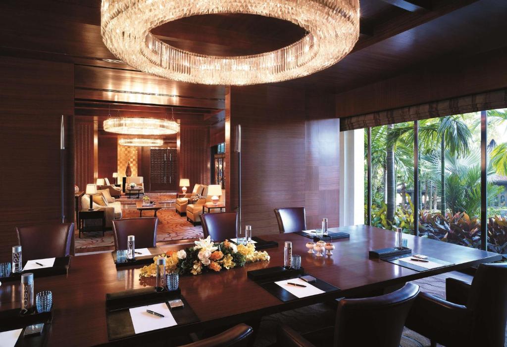 A polished private meeting room with a long conference table and garden-facing windows.