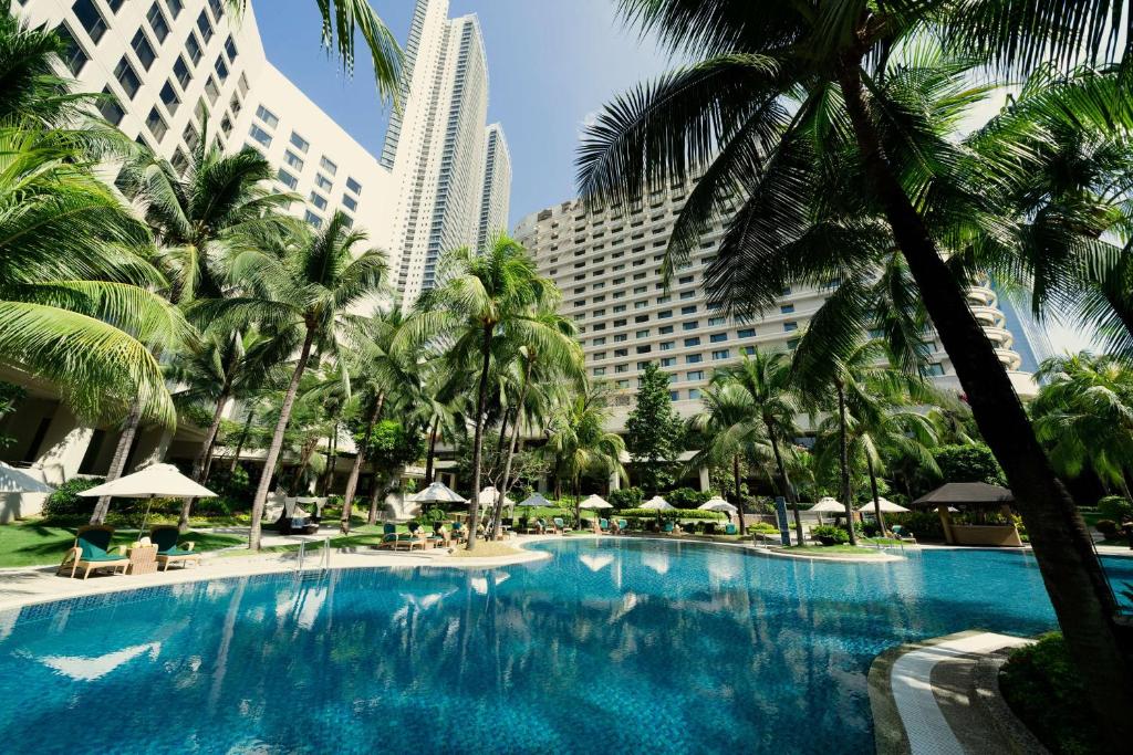 a large swimming pool with palm trees and buildings at Edsa Shangri-La, Manila in Manila