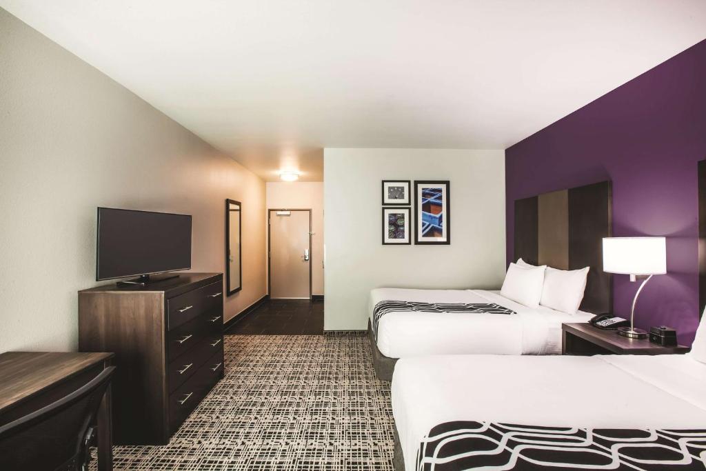 a hotel room with two beds and a flat screen tv at La Quinta by Wyndham Lubbock South in Lubbock