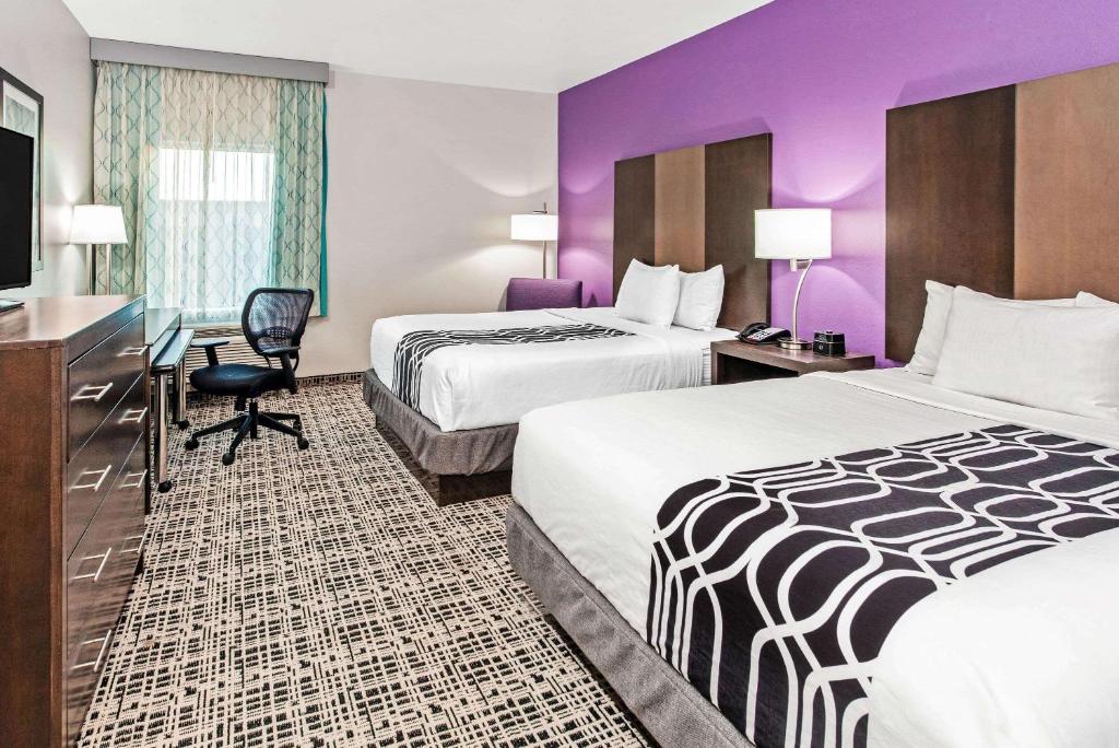 a hotel room with two beds and a flat screen tv at La Quinta by Wyndham Lubbock South in Lubbock