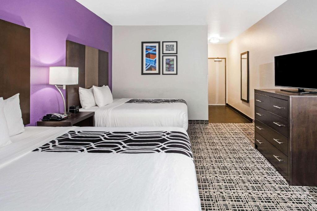 a hotel room with two beds and a flat screen tv at La Quinta by Wyndham Lubbock South in Lubbock
