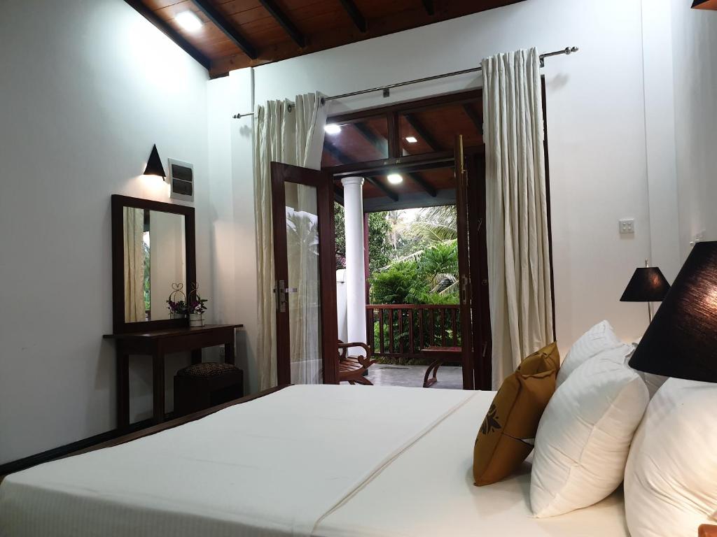een slaapkamer met een bed met een spiegel en een raam bij Olee Villa in Bentota