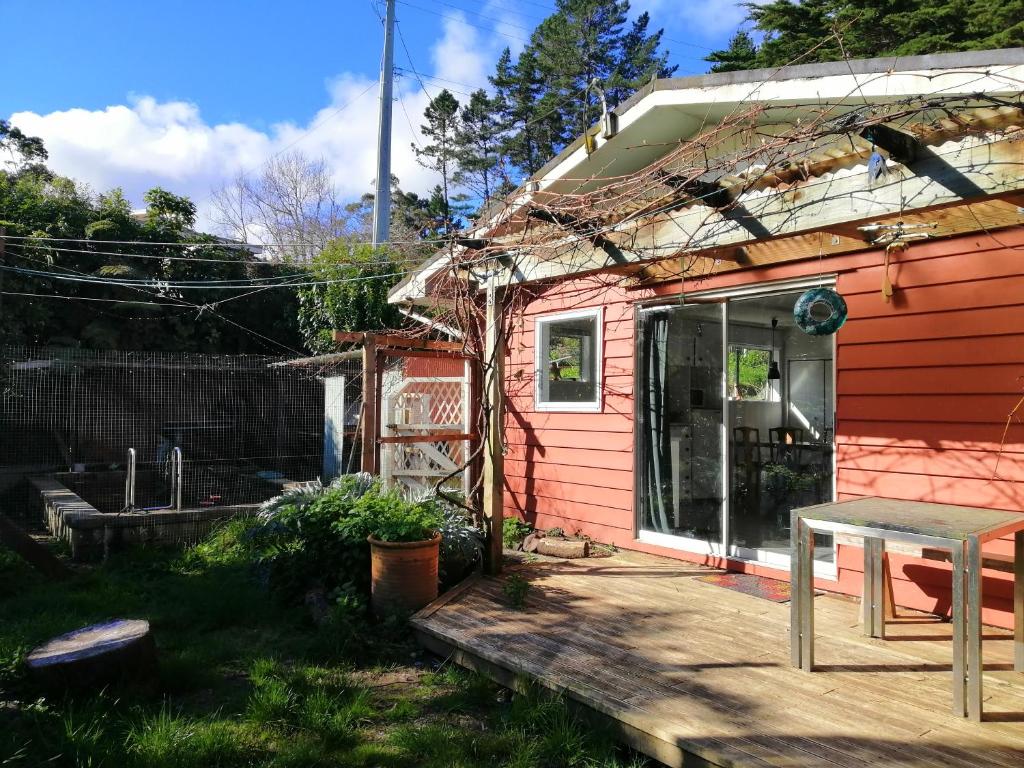 a small pink house with a table on a deck at Cozy guesthouse at the Rabbithole, Akatarawa Valley in Upper Hutt