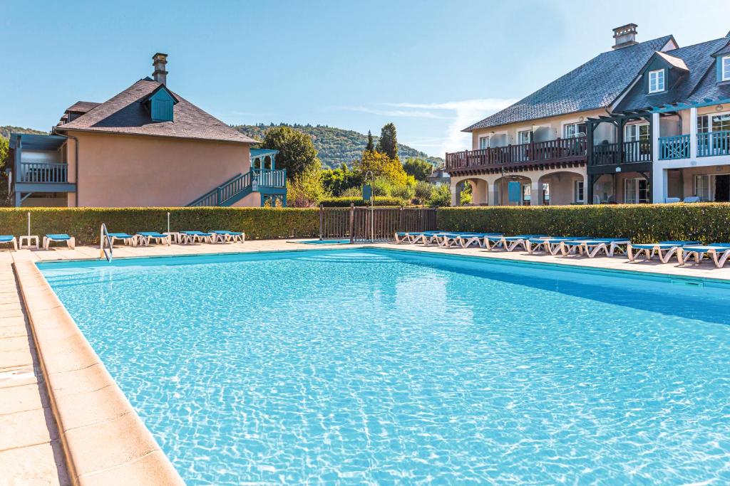 a large swimming pool with chairs in front of a house at Résidence Les Belles Rives - maeva Home in Argentat