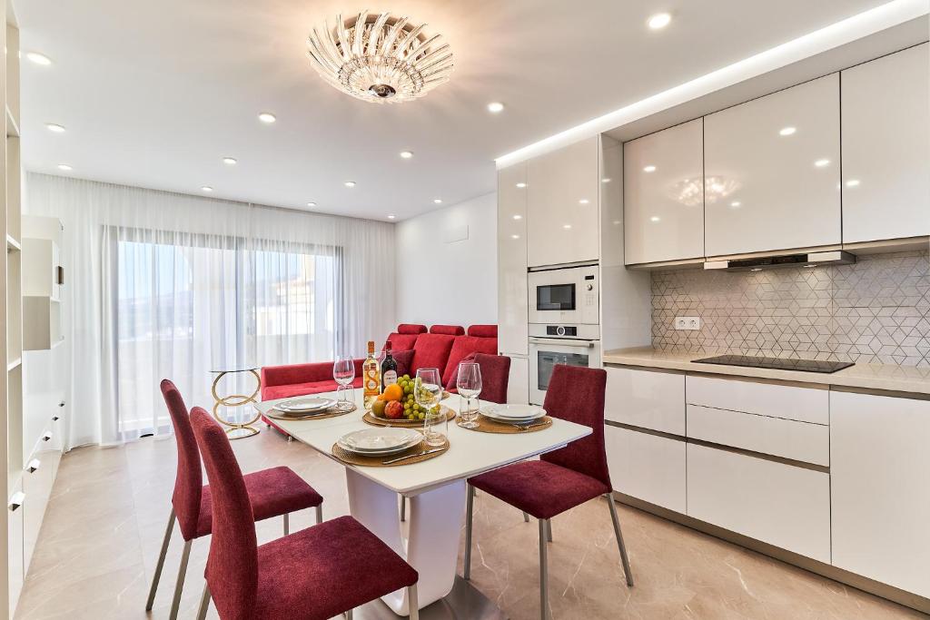 a kitchen and dining room with a table and red chairs at WINDSOR OCEAN PEARL APARTMENT in Adeje