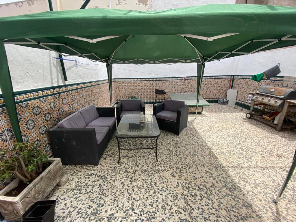 ein Wohnzimmer mit Sofas und einem großen grünen Sonnenschirm in der Unterkunft CASA REFORMADA CON TERRAZA/WIFI/AIRE ACONDICIONADO in Sevilla
