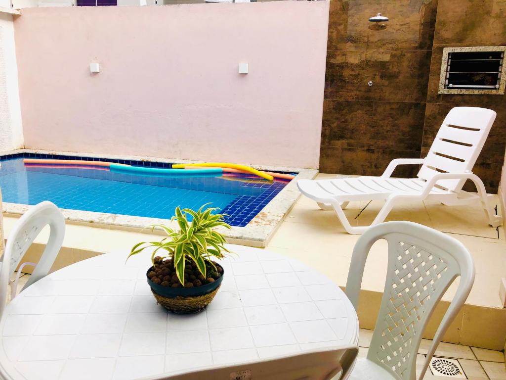a table with a plant on it next to a pool at Dúplex em Porto Seguro com piscina a 8 minutos das praias in Porto Seguro