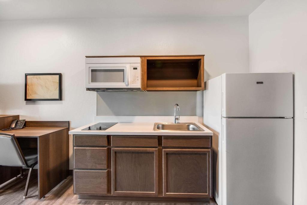 a kitchen with a white refrigerator and a sink at WoodSpring Suites Bakersfield Airport in Bakersfield