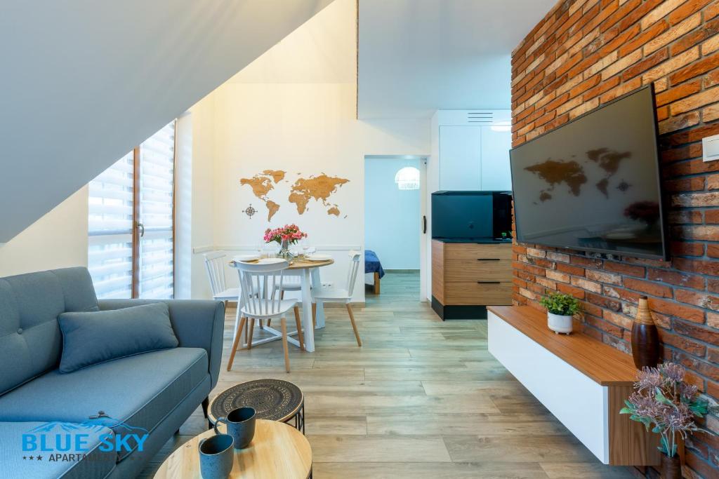 salon z niebieską sofą i ceglaną ścianą w obiekcie Apartamenty BlueSky - Nad Łomnicą15 - Centrum, blisko deptaka w mieście Karpacz