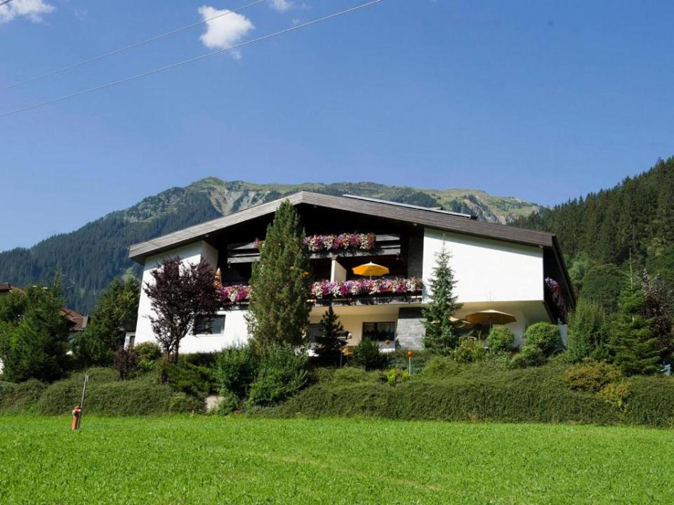 a house with flowers on the balcony in a field at Chalet H Montafon in Gaschurn