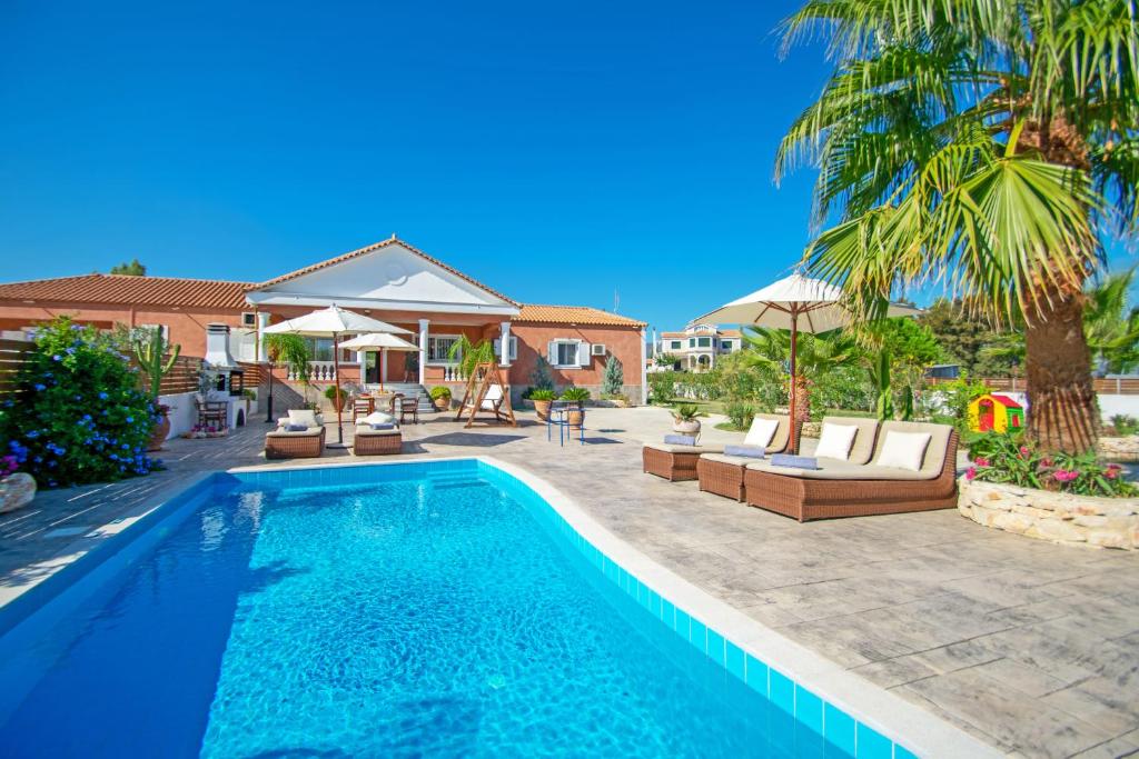a swimming pool with lounge chairs and a villa at Zante Sun II - Getaway Villa! in Kalpaki