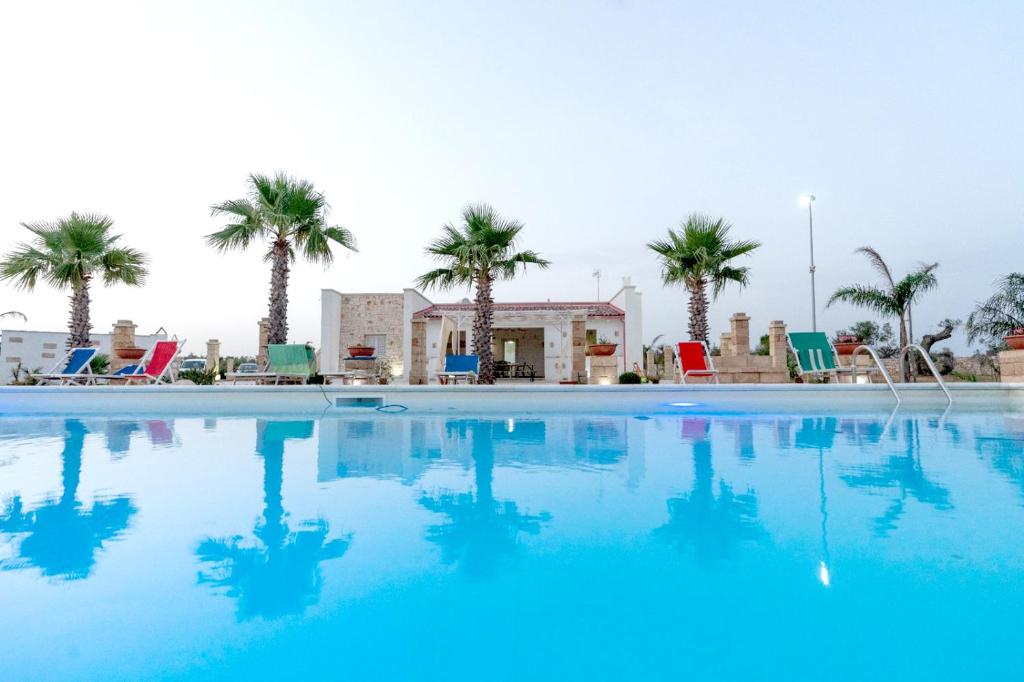 una grande piscina con palme sullo sfondo di Villa Salux by HDSalento a Taurisano