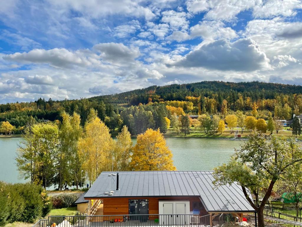 una cabaña de madera con un lago y árboles en el fondo en Penzion U Přehrady, en Luhačovice