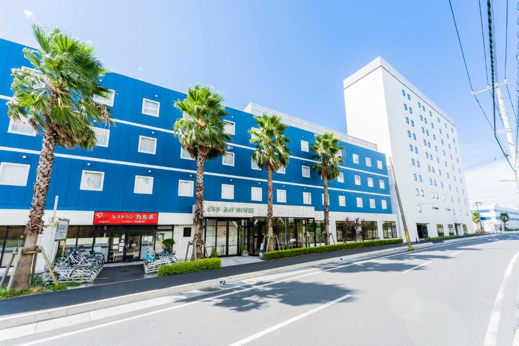 an empty street in front of a blue building with palm trees at CVS Bay Hotel in Urayasu