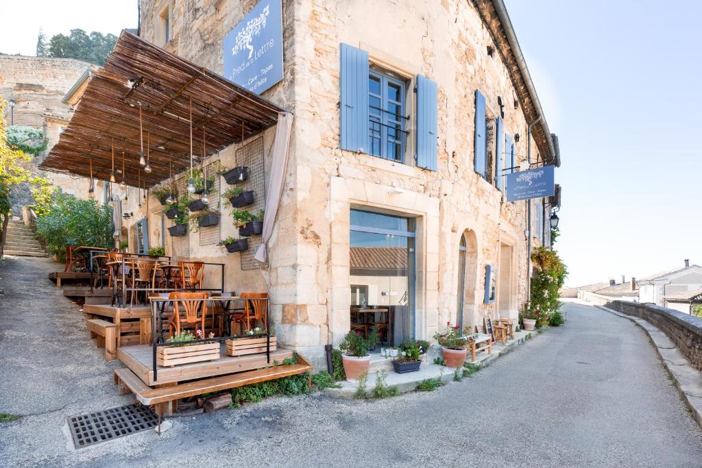 a restaurant with tables and chairs on the side of a building at Le Pied de la Lettre in Grignan
