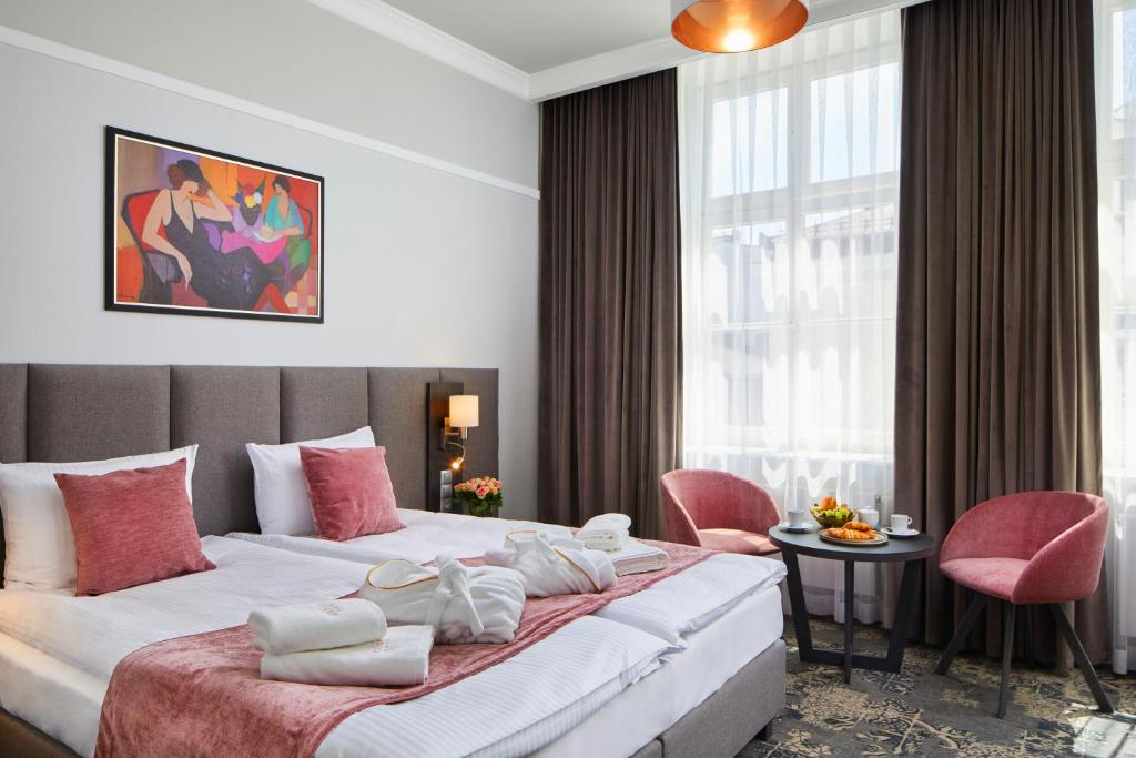 a hotel room with a large bed with pink accents at Hotel Estera in Kraków